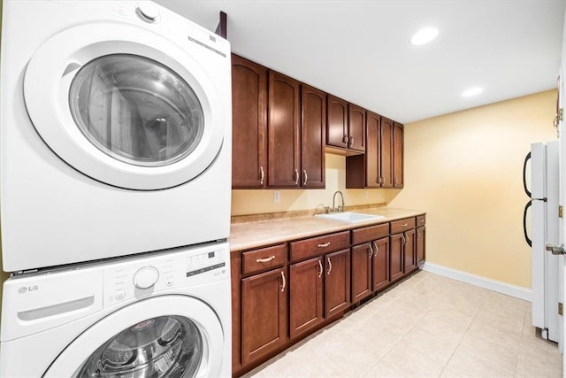 laundry area featuring stacked washer and dryer, sink, and light tile patterned floors