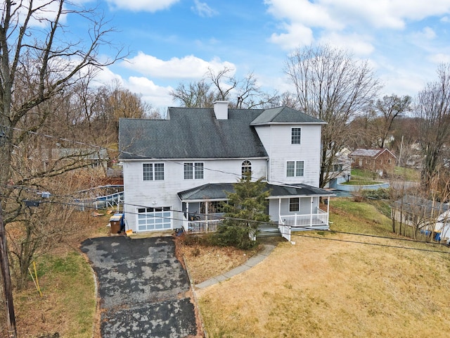 view of front facade featuring a chimney, driveway, covered porch, a front yard, and a garage