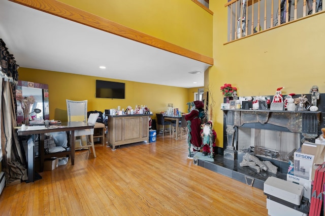 living room featuring baseboard heating, wood finished floors, and a fireplace with raised hearth