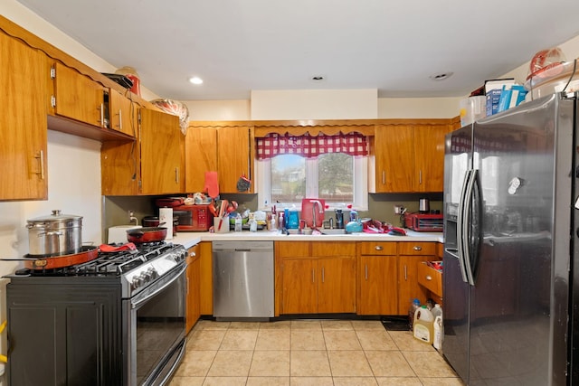 kitchen featuring light countertops, brown cabinets, stainless steel appliances, and a sink