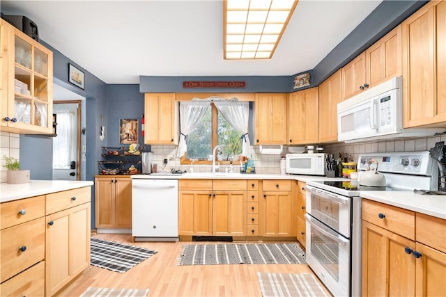 kitchen with sink, light hardwood / wood-style flooring, white appliances, decorative backsplash, and light brown cabinetry