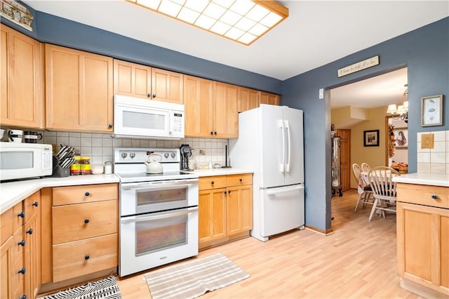 kitchen featuring light brown cabinets, a notable chandelier, backsplash, light hardwood / wood-style floors, and white appliances