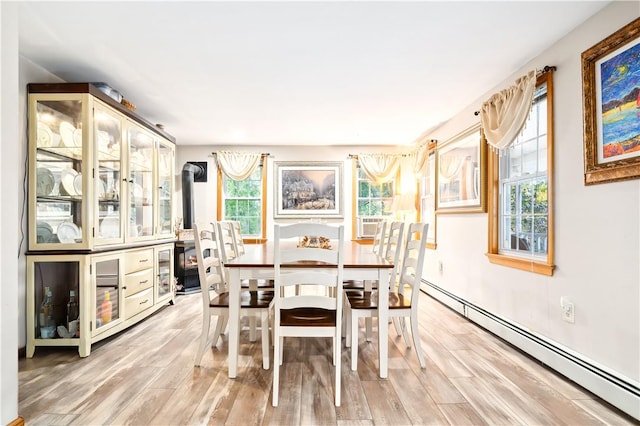 dining area featuring light hardwood / wood-style floors, a healthy amount of sunlight, and a baseboard heating unit