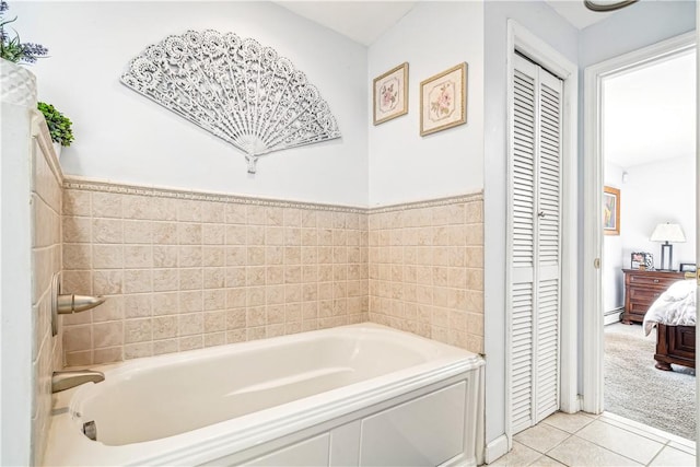 bathroom with tile patterned floors, a bathing tub, tile walls, and a baseboard radiator