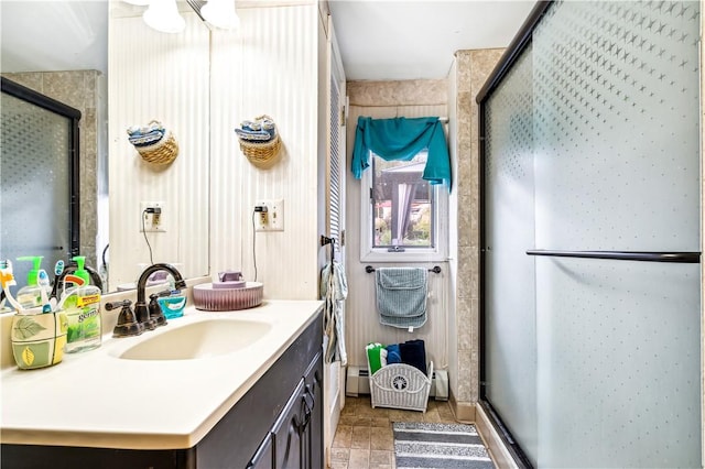 bathroom featuring baseboard heating, vanity, and a shower with shower door