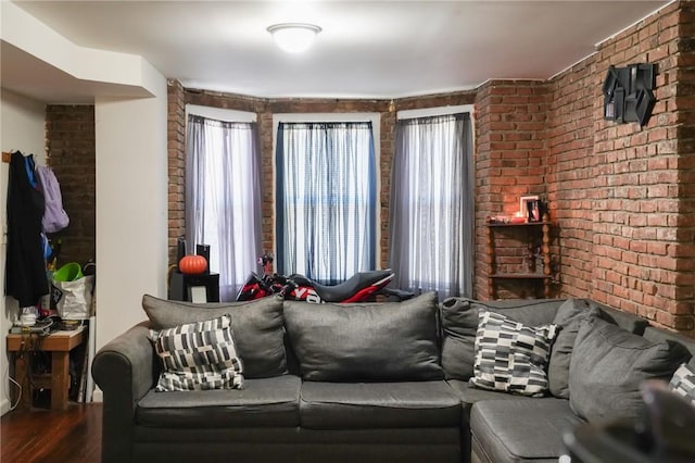 living room with wood-type flooring and brick wall