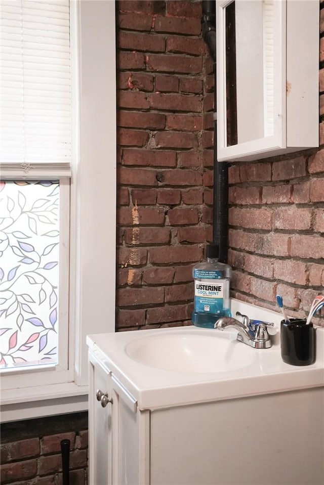 bathroom with vanity and brick wall