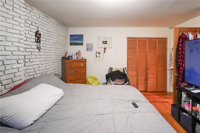 bedroom with a closet, brick wall, and light hardwood / wood-style floors