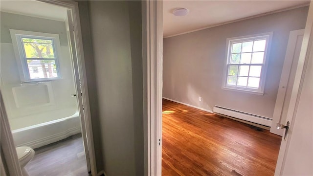 bathroom with ornamental molding, hardwood / wood-style flooring, toilet, and a baseboard heating unit