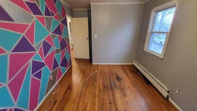 spare room featuring hardwood / wood-style flooring and a baseboard heating unit