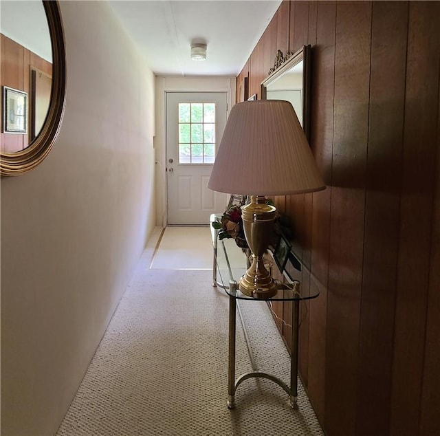 corridor featuring wood walls and light carpet