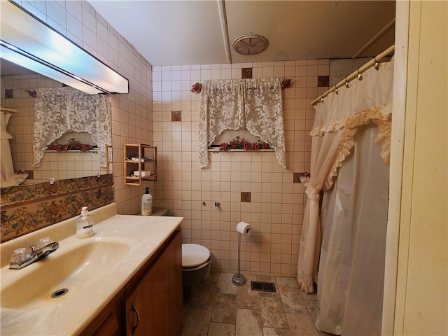 bathroom with vanity, tile walls, and toilet