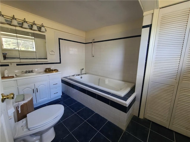 bathroom featuring tile patterned flooring, vanity, toilet, and tiled bath