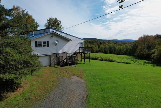 view of side of property featuring a lawn, a wooden deck, and a garage