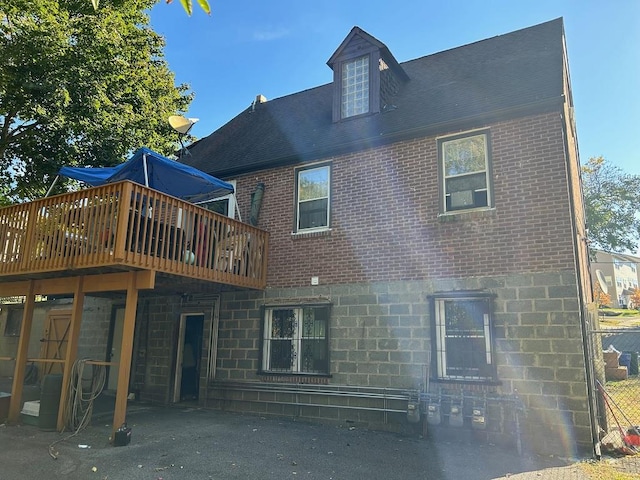 rear view of property featuring a wooden deck and a patio