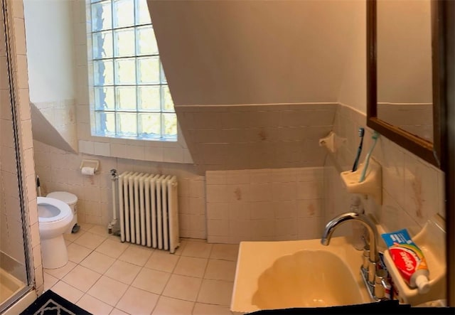 bathroom with toilet, plenty of natural light, radiator, and tile walls