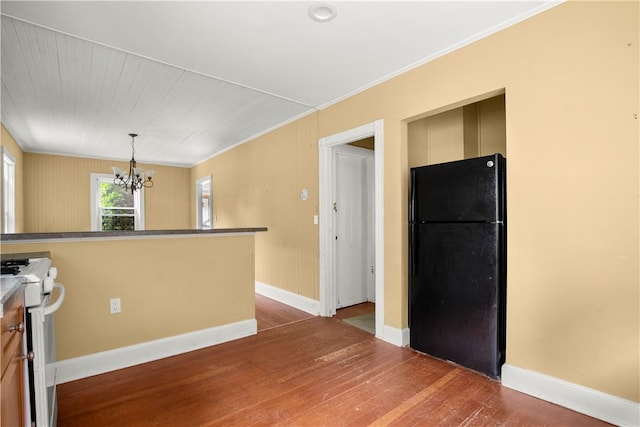 kitchen with black refrigerator, ornamental molding, a notable chandelier, white stove, and dark hardwood / wood-style floors