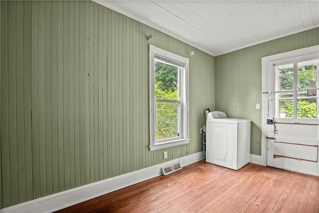 washroom with washer / dryer, light hardwood / wood-style flooring, a wealth of natural light, and wooden walls