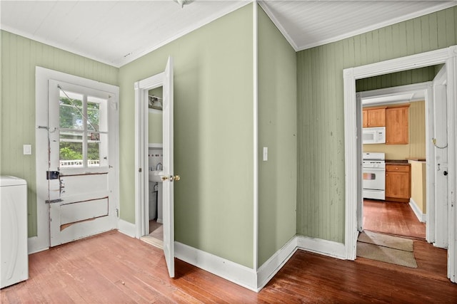 interior space featuring wood walls, light hardwood / wood-style floors, ornamental molding, and washer / clothes dryer