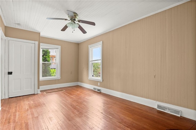 unfurnished bedroom with ceiling fan, wooden walls, and wood-type flooring