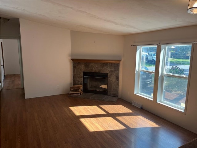 unfurnished living room with hardwood / wood-style floors, a stone fireplace, and a healthy amount of sunlight