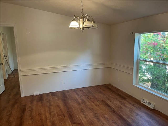 spare room featuring dark hardwood / wood-style flooring and a notable chandelier