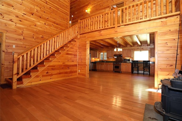 unfurnished living room with a wood stove, wooden walls, and light hardwood / wood-style floors