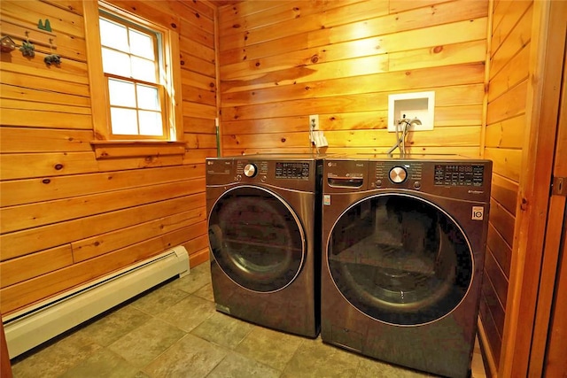 clothes washing area with independent washer and dryer, baseboard heating, and wood walls