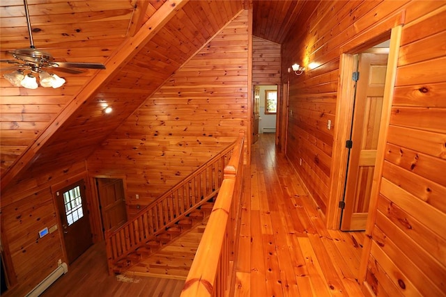 hall featuring plenty of natural light, wood walls, and vaulted ceiling