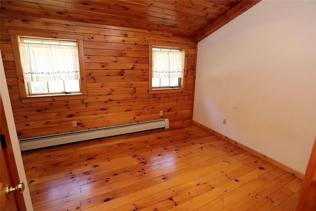 empty room with light wood-type flooring, wooden ceiling, a wealth of natural light, and a baseboard heating unit