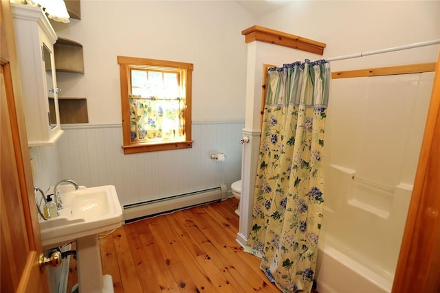 bathroom featuring toilet, shower / bathtub combination with curtain, a baseboard radiator, and hardwood / wood-style flooring