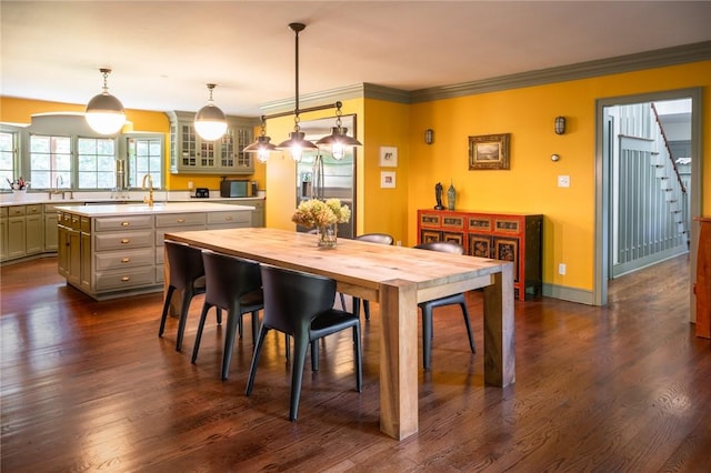 dining space featuring dark hardwood / wood-style flooring, crown molding, and sink