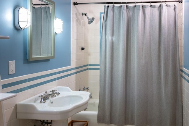 bathroom featuring tile walls, shower / bath combo with shower curtain, and sink