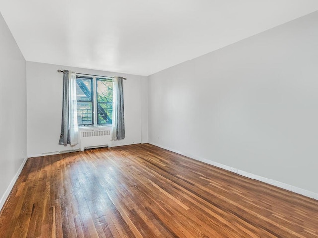 spare room with wood-type flooring and radiator heating unit