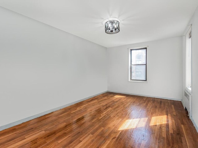 unfurnished room featuring radiator and dark hardwood / wood-style floors