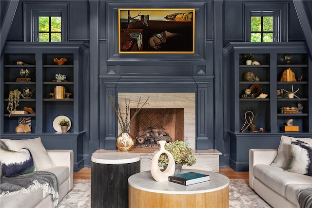 living room with hardwood / wood-style flooring, built in shelves, a healthy amount of sunlight, and a fireplace