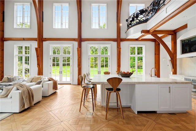 kitchen featuring white cabinetry, light stone countertops, plenty of natural light, and a high ceiling