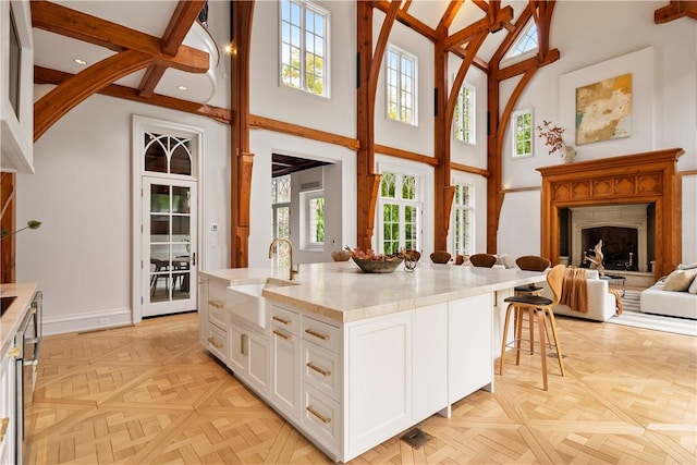 kitchen with a center island with sink, white cabinetry, a healthy amount of sunlight, and sink