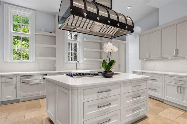 kitchen featuring white cabinets, a center island, backsplash, and island range hood