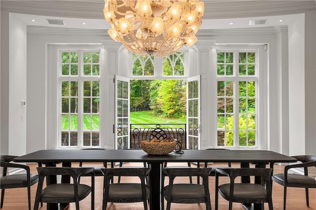 dining space with hardwood / wood-style floors, a notable chandelier, and crown molding