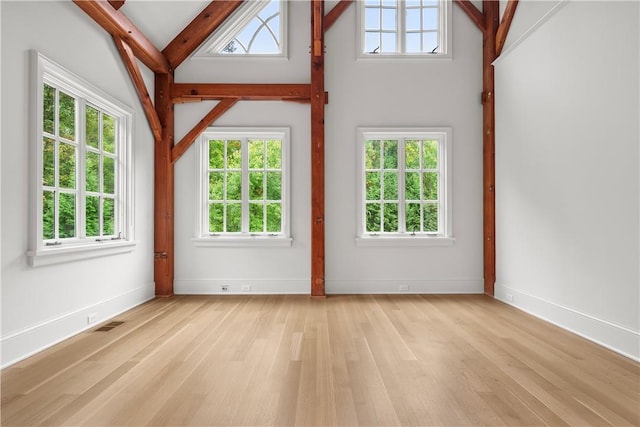 interior space featuring beamed ceiling, high vaulted ceiling, and light hardwood / wood-style flooring