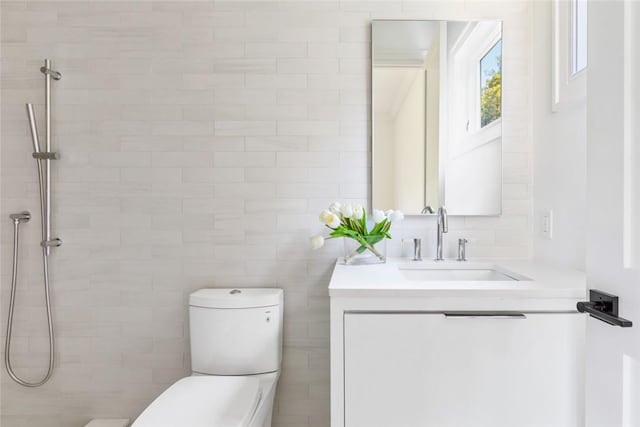 bathroom featuring toilet, vanity, and tiled shower