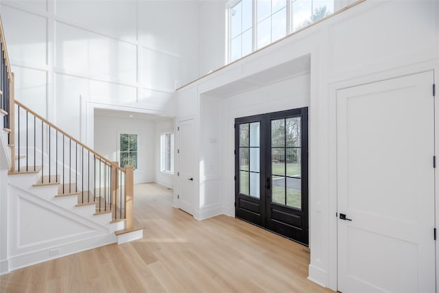 foyer entrance featuring a high ceiling, french doors, and light wood-type flooring