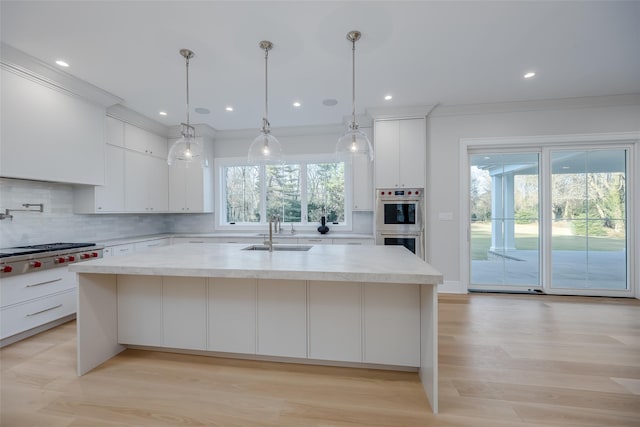 kitchen with decorative light fixtures, stainless steel appliances, tasteful backsplash, sink, and a center island with sink