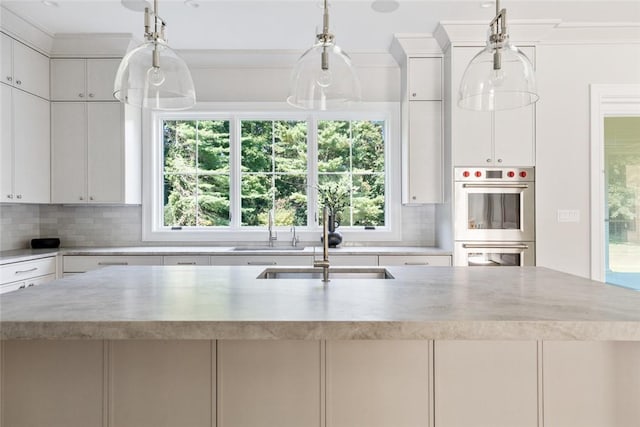 kitchen with decorative light fixtures, white cabinets, stainless steel double oven, and sink