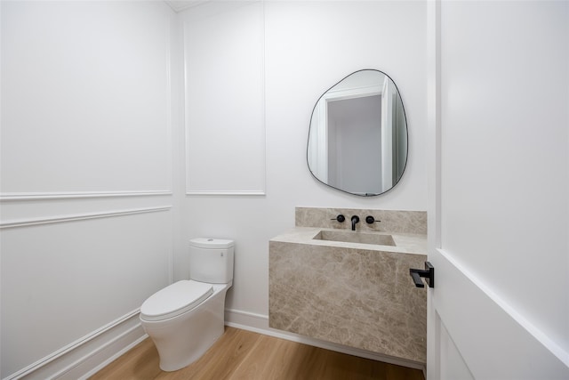 bathroom with hardwood / wood-style flooring, sink, and toilet