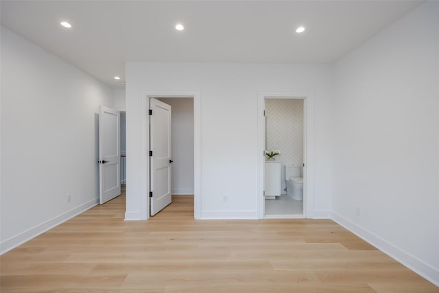 unfurnished bedroom featuring ensuite bath, a spacious closet, and light hardwood / wood-style flooring