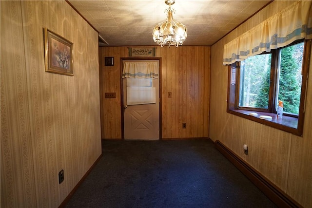 carpeted spare room featuring a baseboard radiator, an inviting chandelier, and wood walls