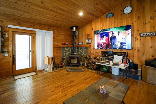 living room featuring a wood stove, hardwood / wood-style floors, wooden ceiling, and lofted ceiling