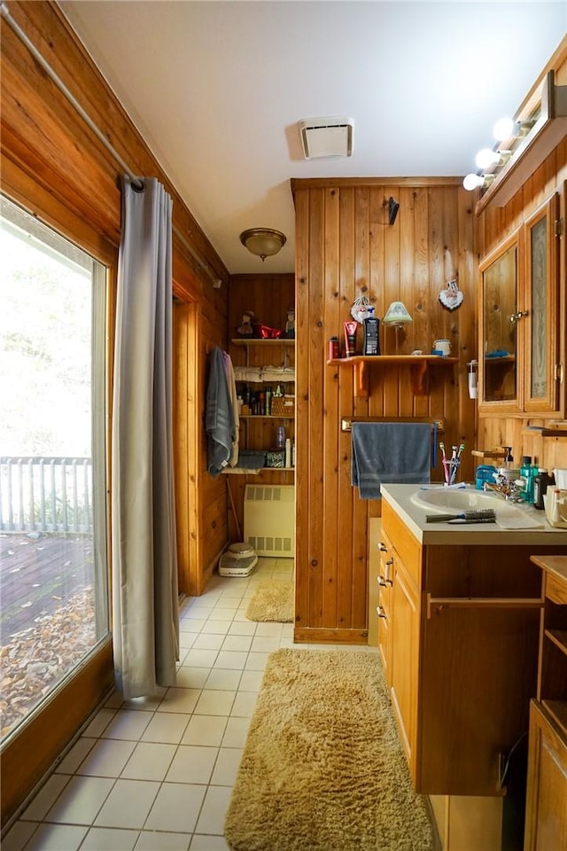 bathroom featuring tile patterned flooring, radiator heating unit, vanity, and wooden walls